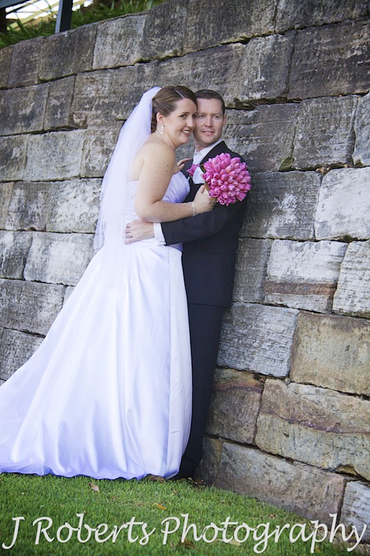Bride and groom leaning against sandstone wall at Blues Point - wedding photography sydney